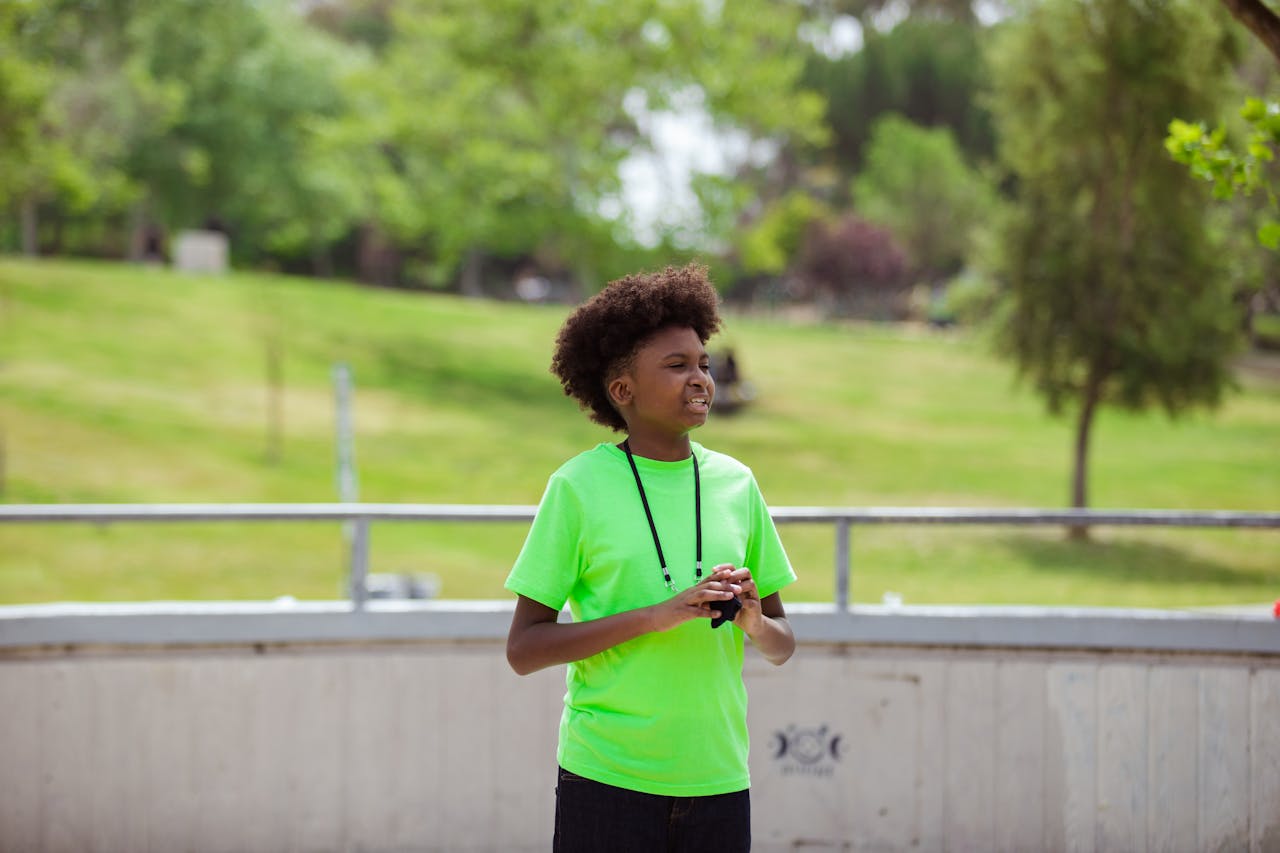 A teenager in a neon green shirt enjoys outdoor activities at the park on a sunny day.